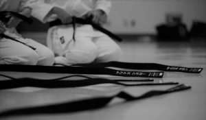 Black belt (martial arts) laid out on dojo floor with students