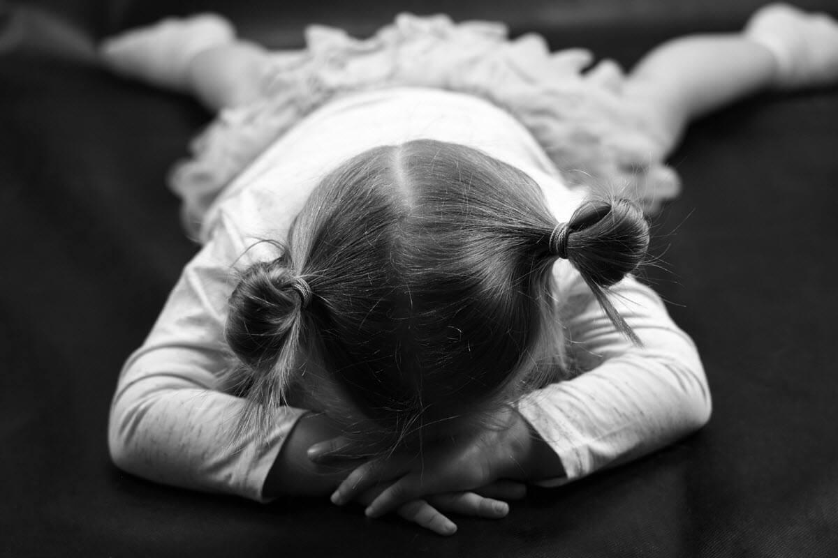 Little girl with pigtails in white lying on the floor