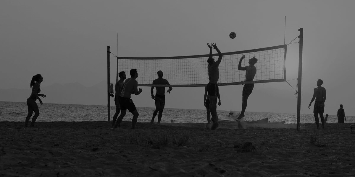 Silhouettes of beach volleyball players at the beach with sun shining