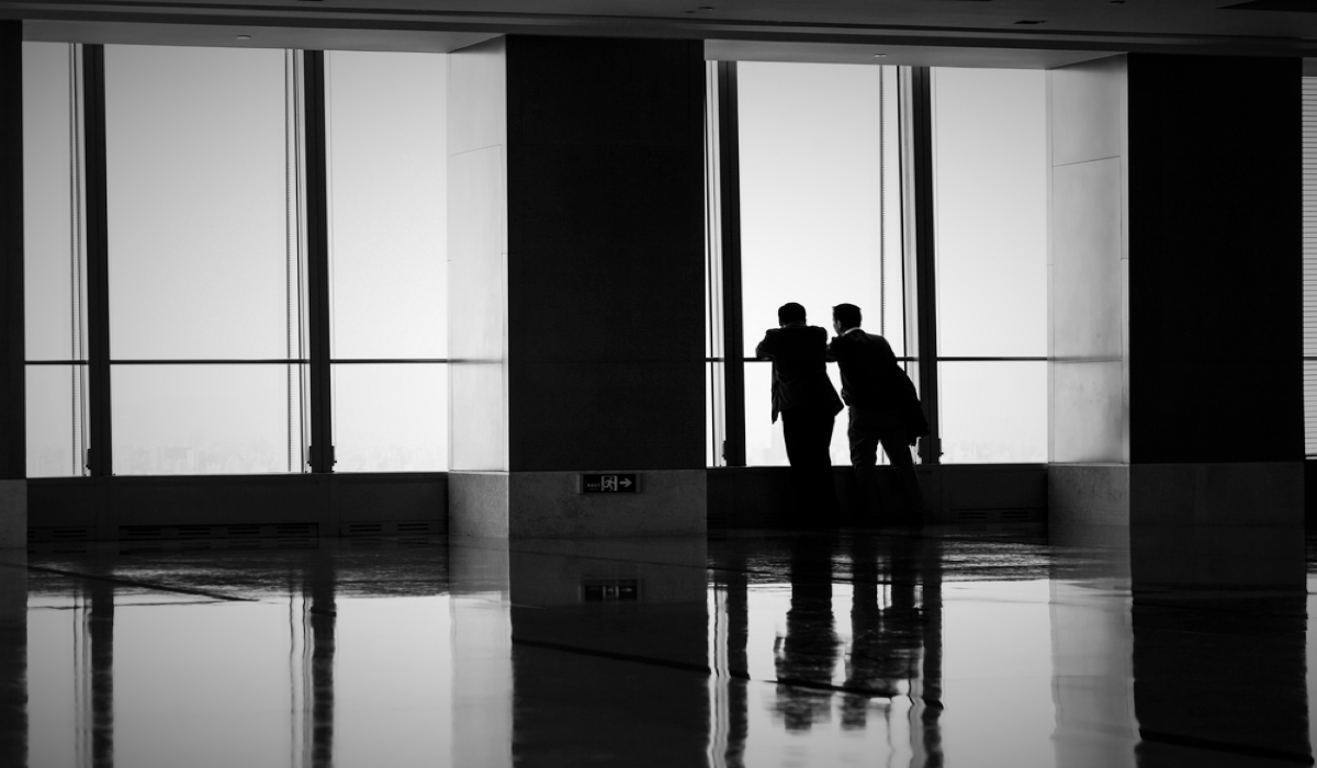 Two executives whispering in an empty hallway