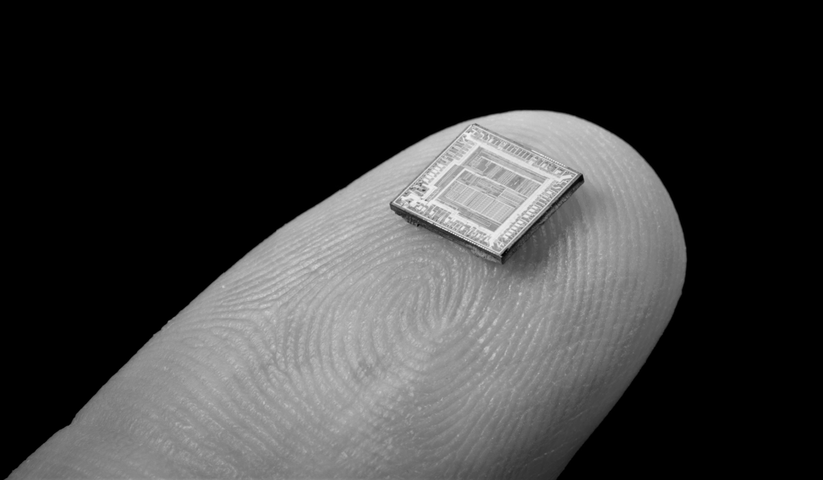 A microchip sits on the tip of a person's finger