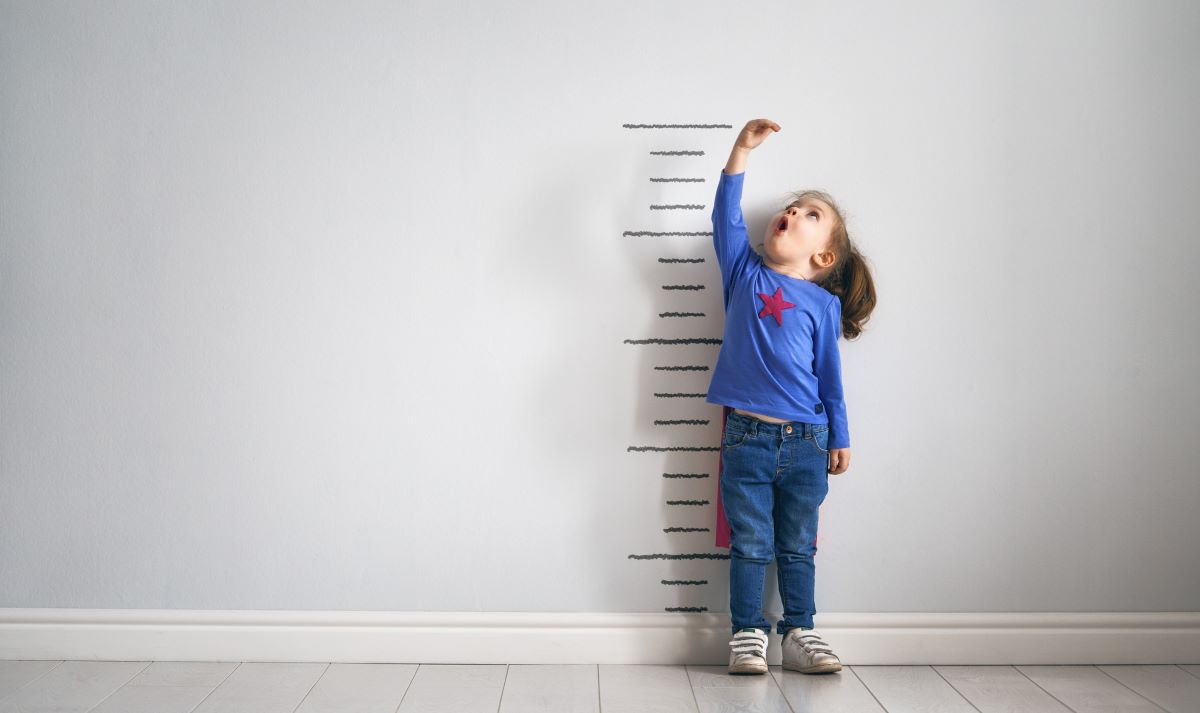 Little girl measures her growth on the wall
