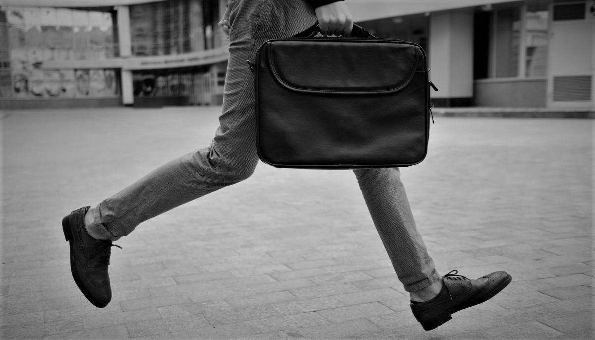 Legs of person, holding a briefcase, running