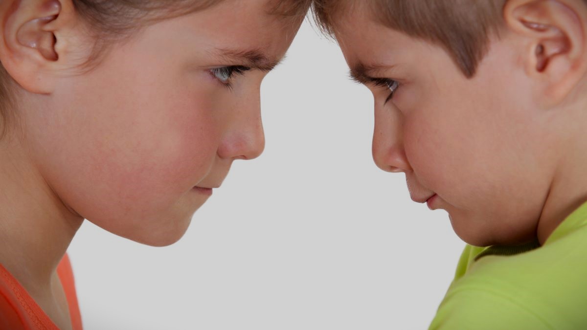 Two young siblings staring head to head in argument