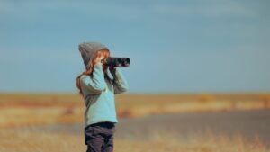 Girl with binoculars monitors distant view