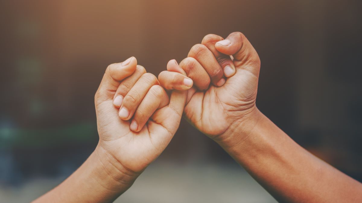 Two hands forming a pinky swear