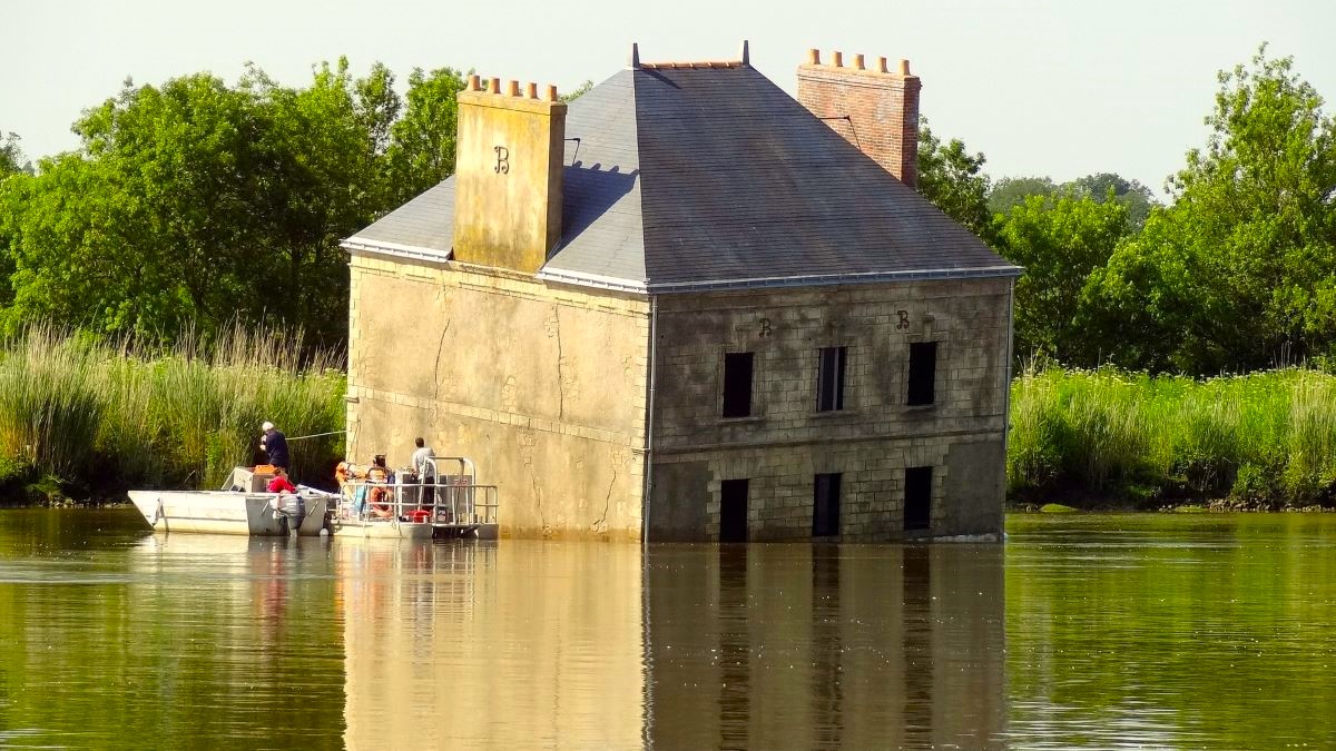 A house sinking into a pond