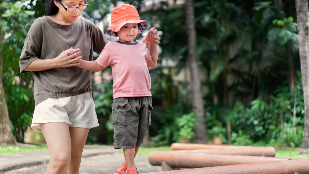 mother stabilizes son on beam